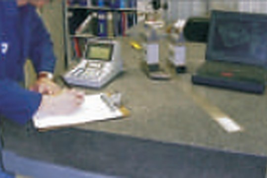 Engineer recording dimensional measurements at a granite surface plate